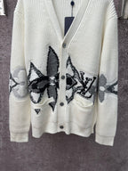 Cream knit cardigan with black butterfly-style embroidery and front patch pockets