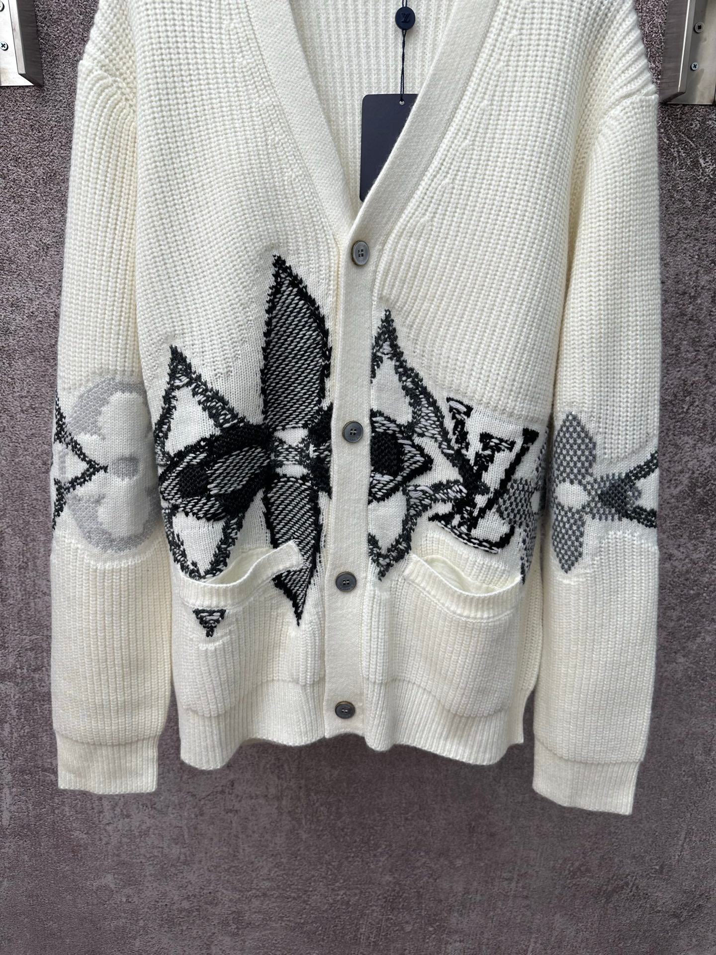 Cream knit cardigan with black butterfly-style embroidery and front patch pockets