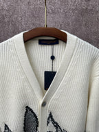 Cream knit cardigan neckline with V-neck and black butterfly-style motif on chest