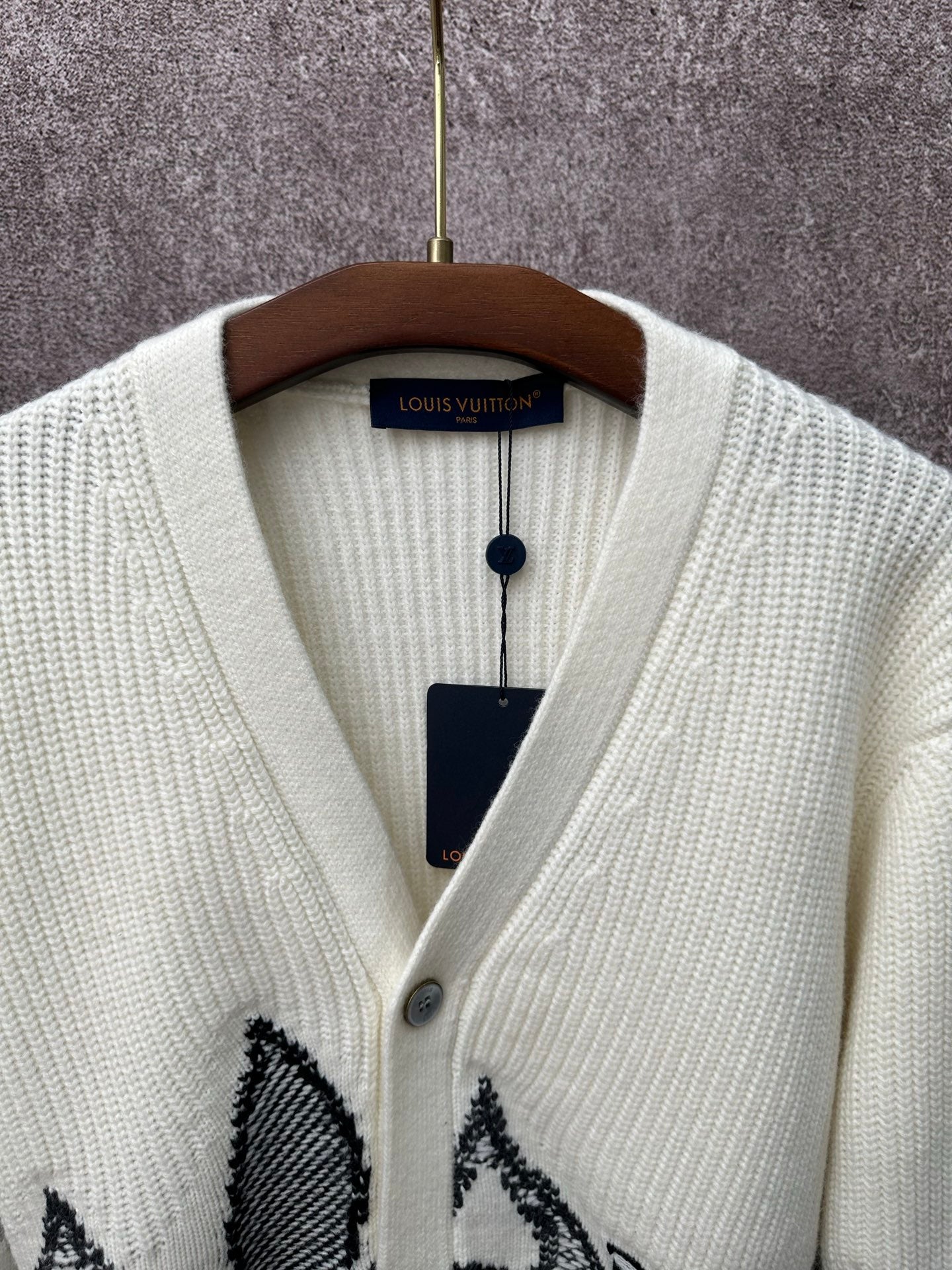 Cream knit cardigan neckline with V-neck and black butterfly-style motif on chest