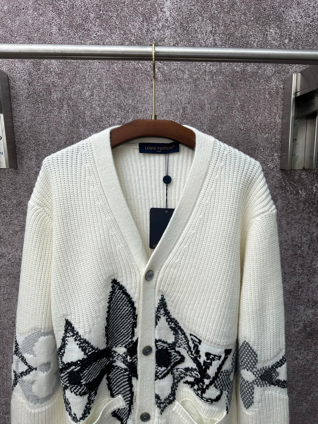Cream knit cardigan with V-neck, button placket, and large black butterfly-style motifs