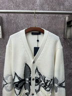 Cream knit cardigan with V-neck, button placket, and large black butterfly-style motifs
