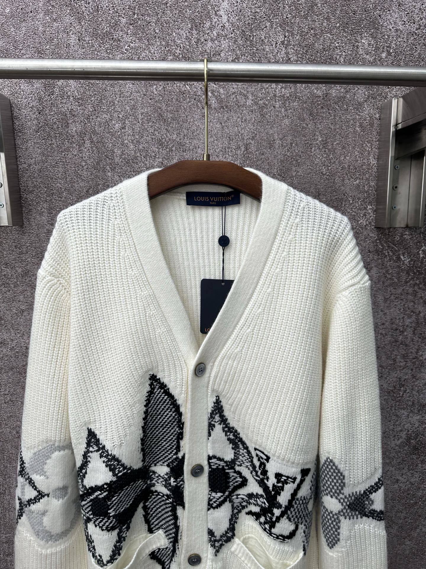 Cream knit cardigan with V-neck, button placket, and large black butterfly-style motifs