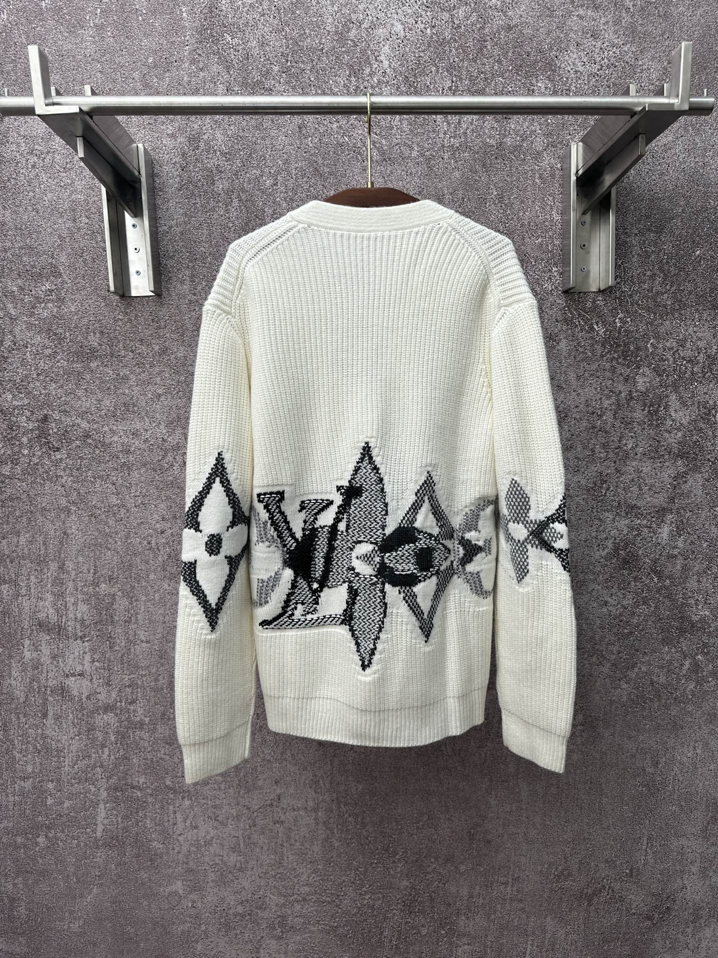 Cream knit cardigan with black butterfly-style motif embroidery across the back