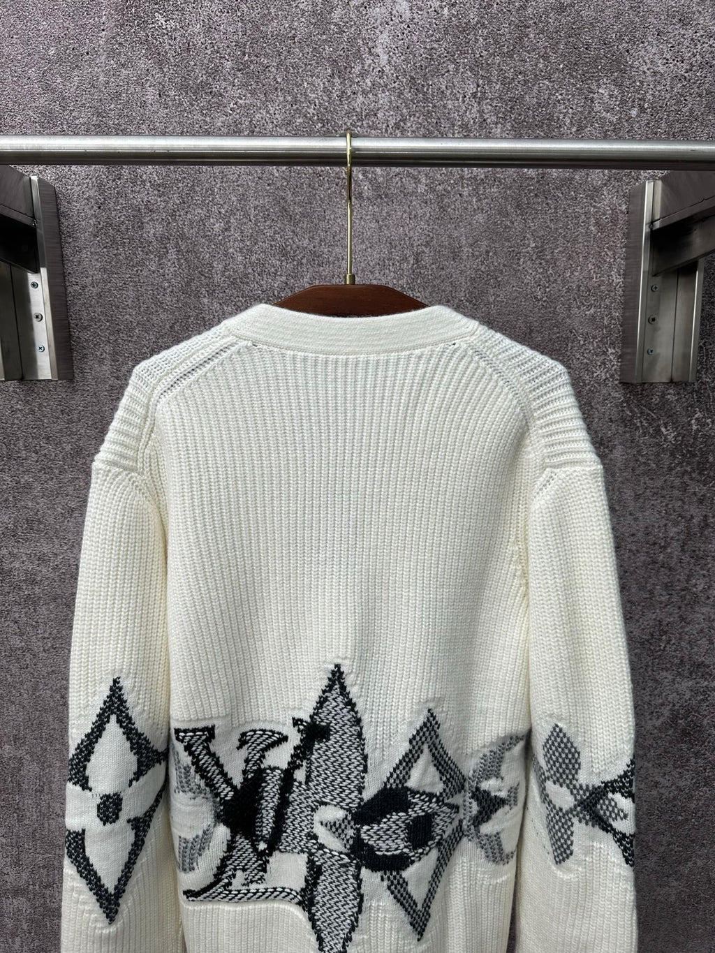 Back of cream knit cardigan with black butterfly-style motif band across the hem