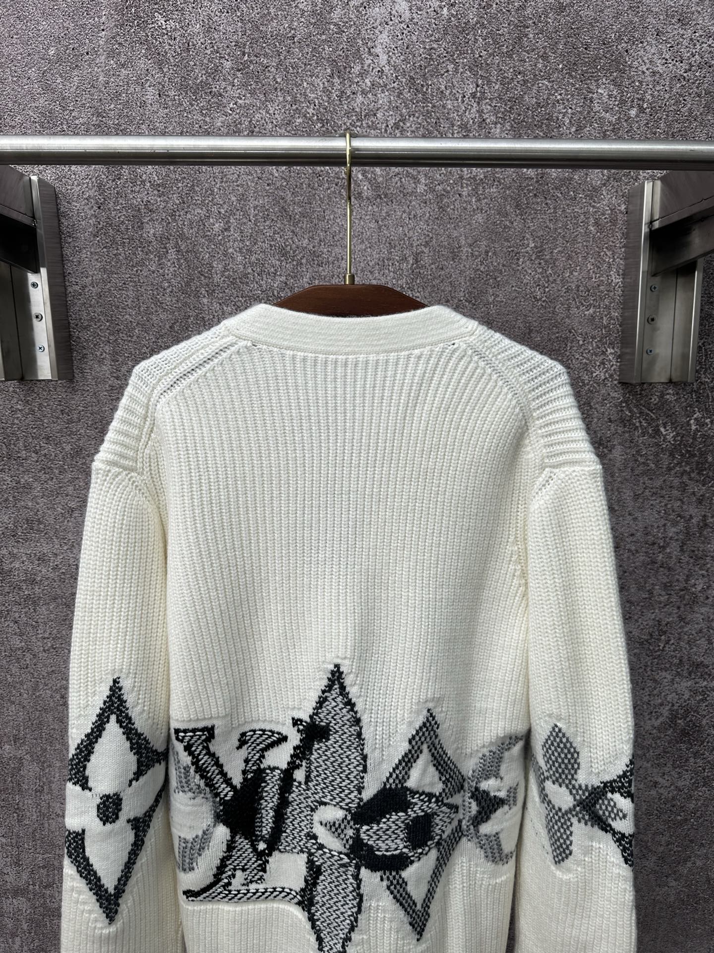 Back of cream knit cardigan with black butterfly-style motif band across the hem
