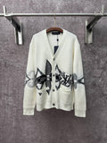 Cream knit cardigan with black patterned butterfly-style motifs and button front