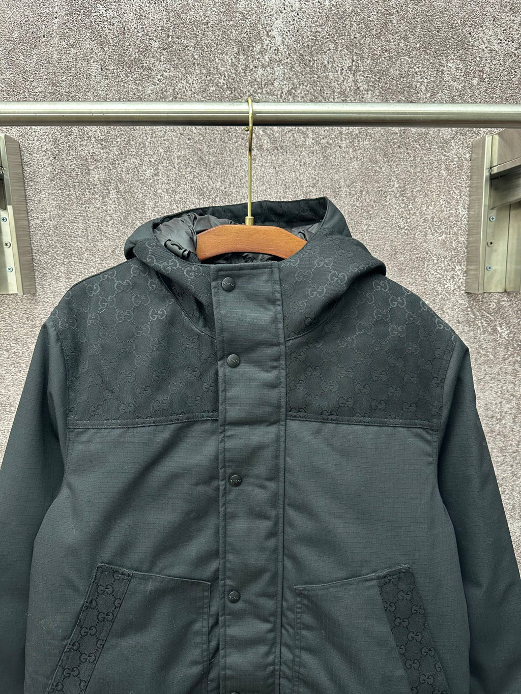 Dark hooded jacket with textured monogram panels and front buttons