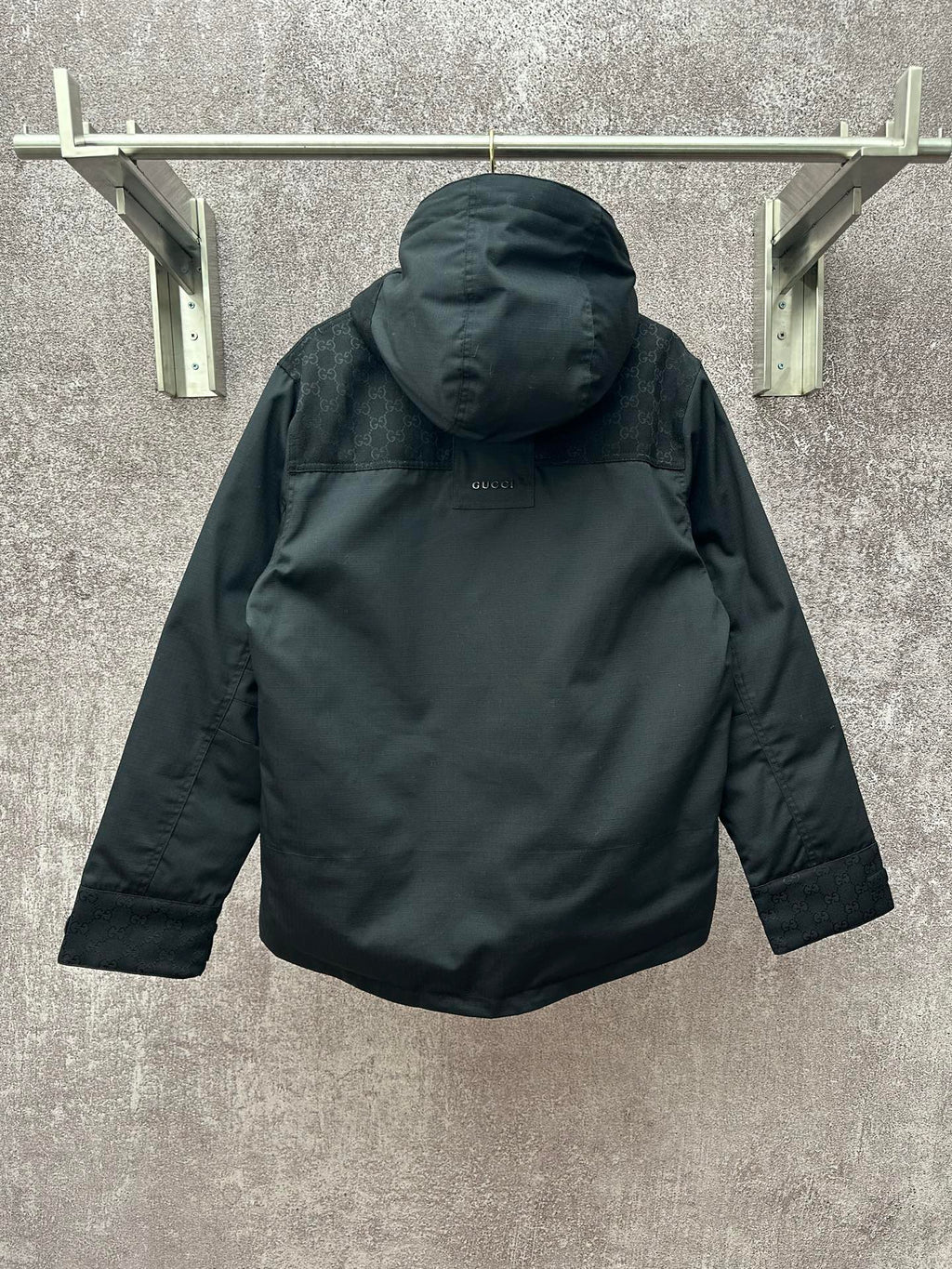 Back view of dark hooded jacket with hood and buttoned center placket