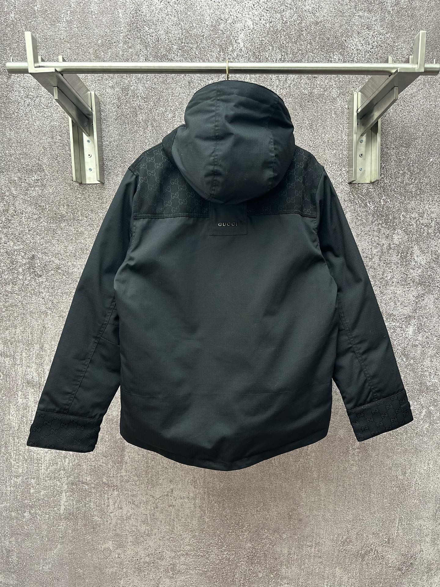 Back view of dark hooded jacket with hood and buttoned center placket