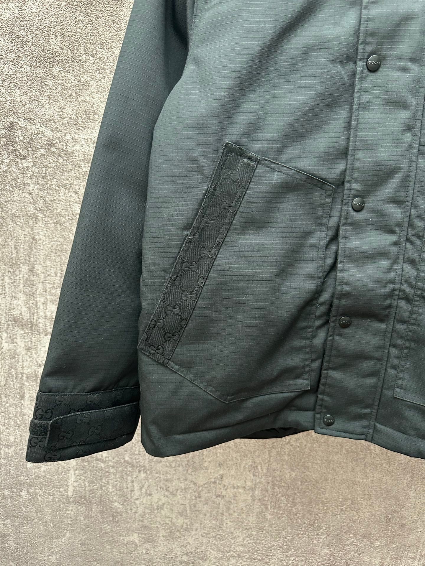 Dark jacket sleeve and front pocket with monogram trim and snap buttons