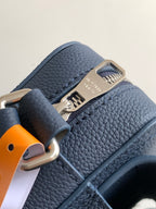 Blue pebbled leather bag close-up with metal clasp and embossed logo plate