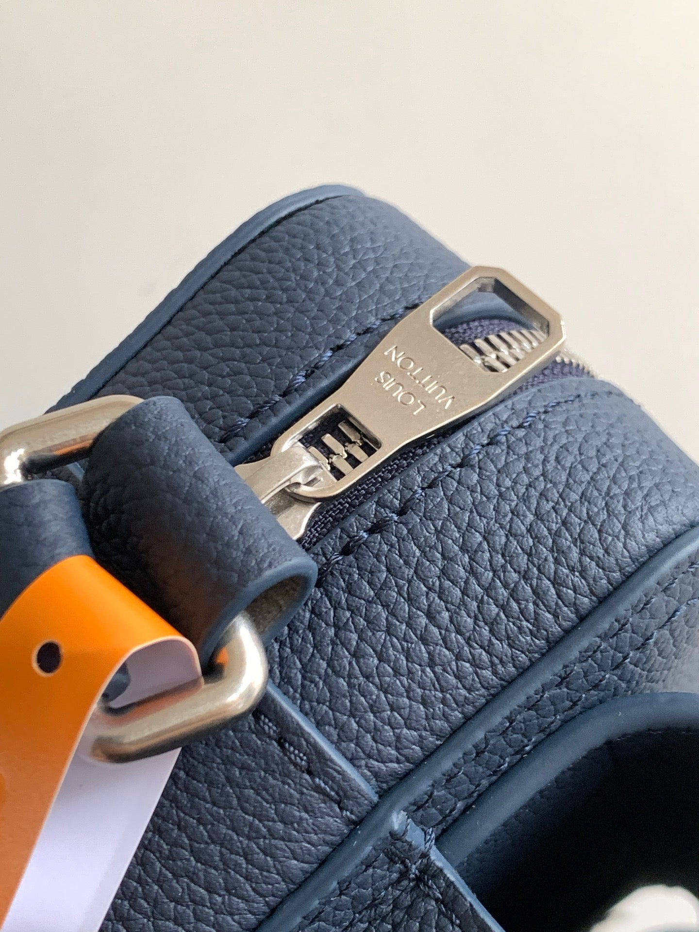 Blue pebbled leather bag close-up with metal clasp and embossed logo plate