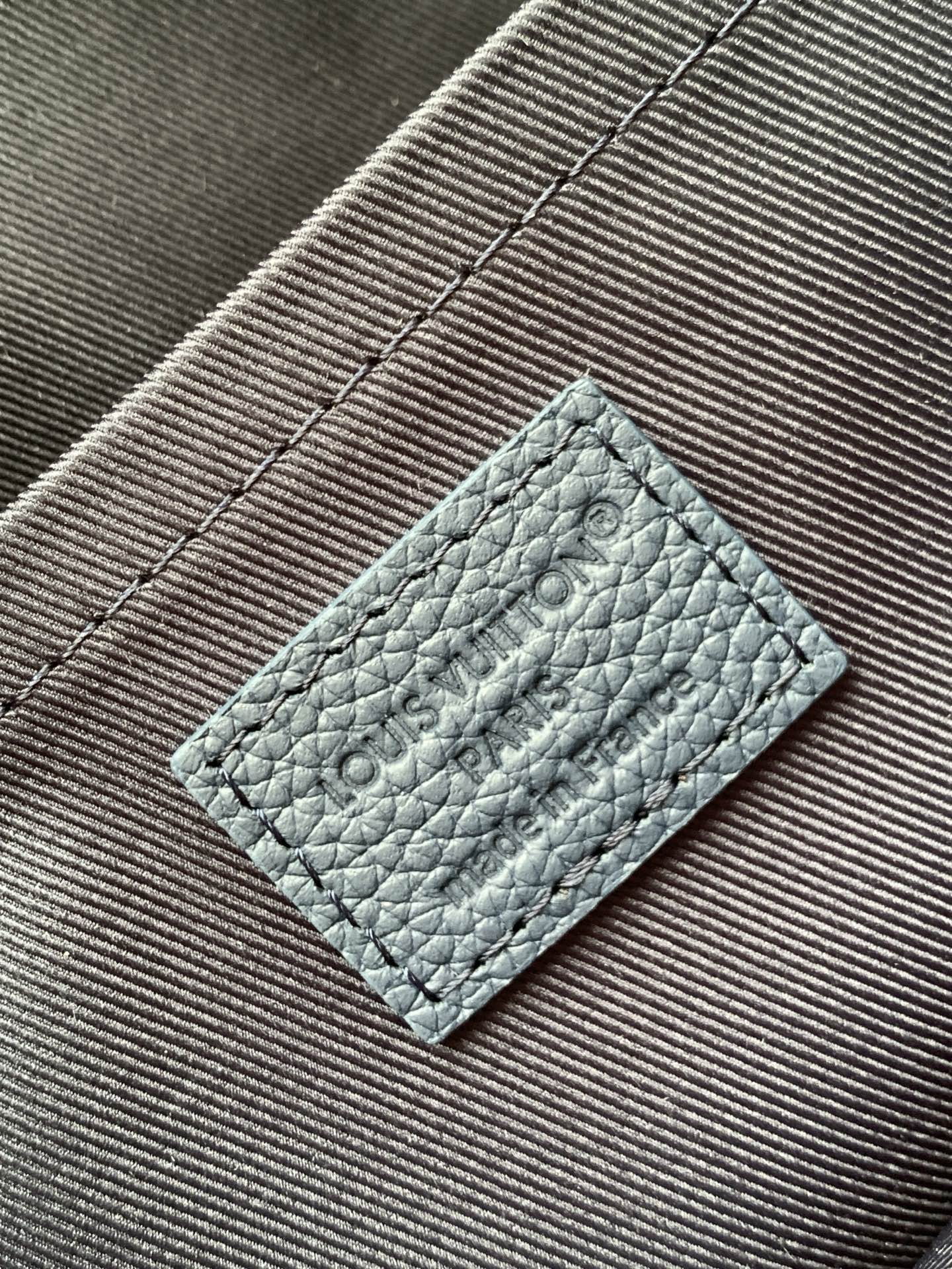 Men's Louis Vuitton light blue leather tag with embossed logo on fabric