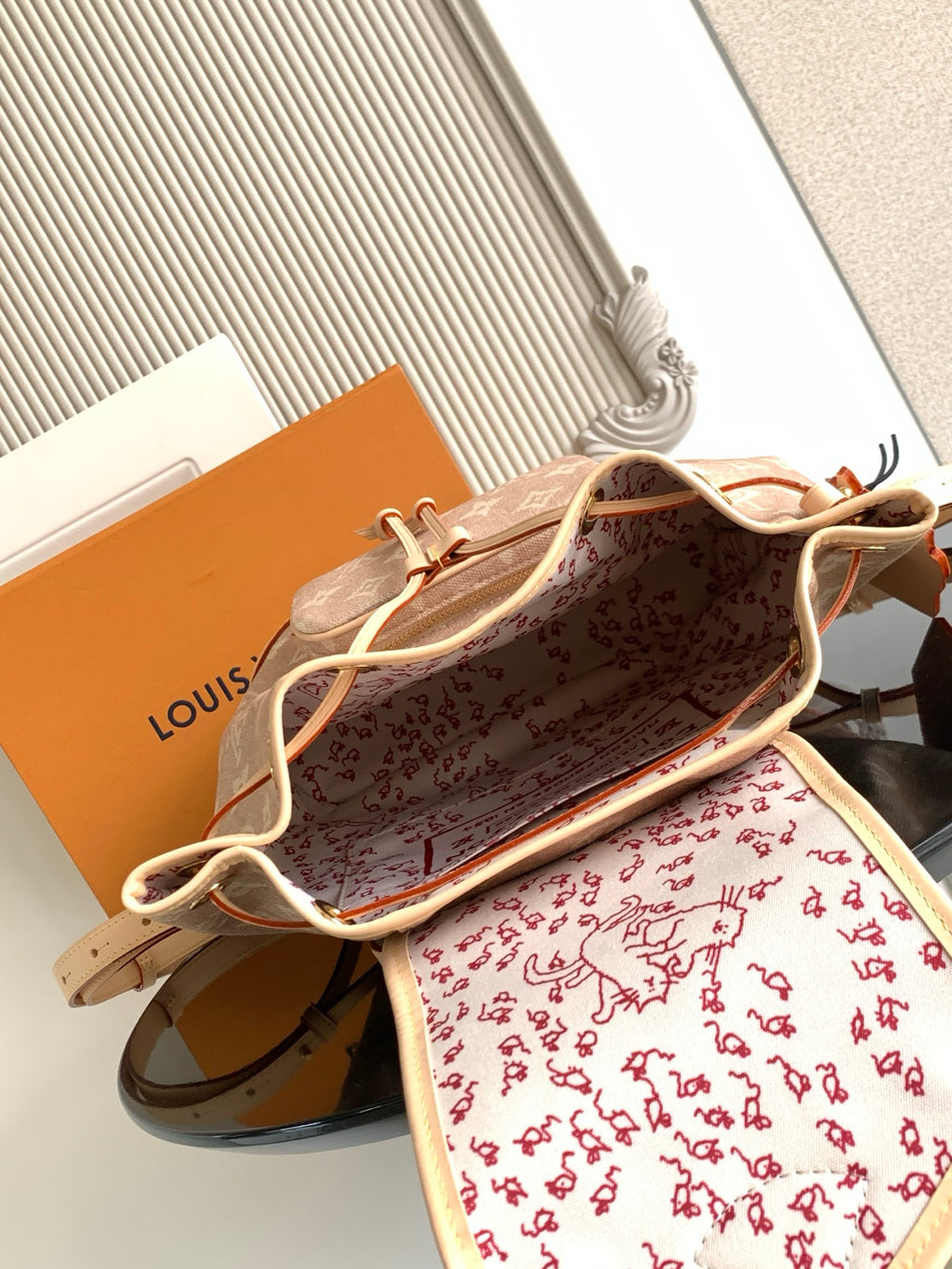 Louis Vuitton monogram mini bag open, showing red patterned lining and tan leather trim.