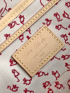 Louis Vuitton leather label patch on red-and-white patterned canvas lining with stitching.