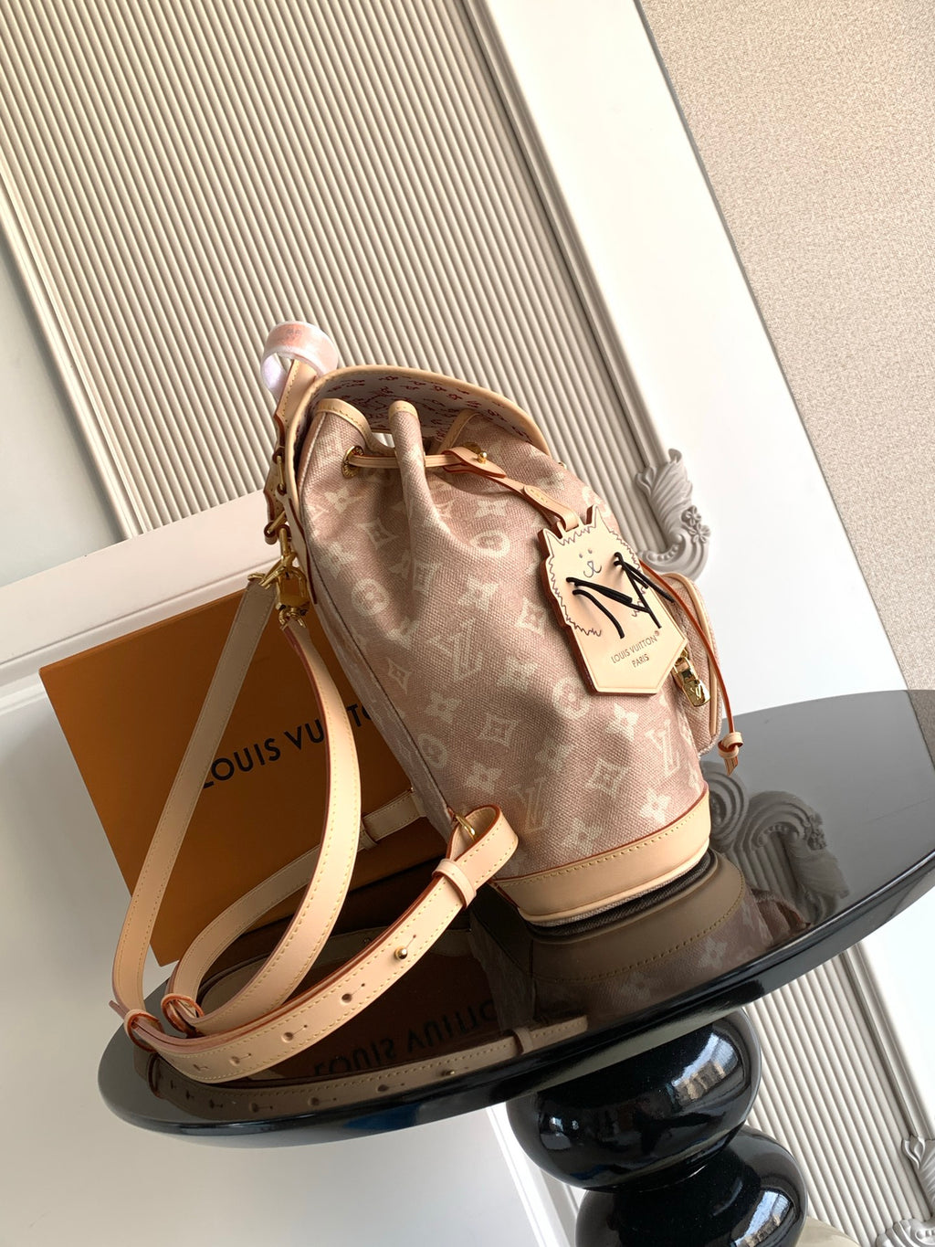 Louis Vuitton monogram mini backpack with tan shoulder strap and leather tag at side.