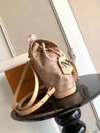 Louis Vuitton monogram mini backpack with tan shoulder strap and leather tag at side.