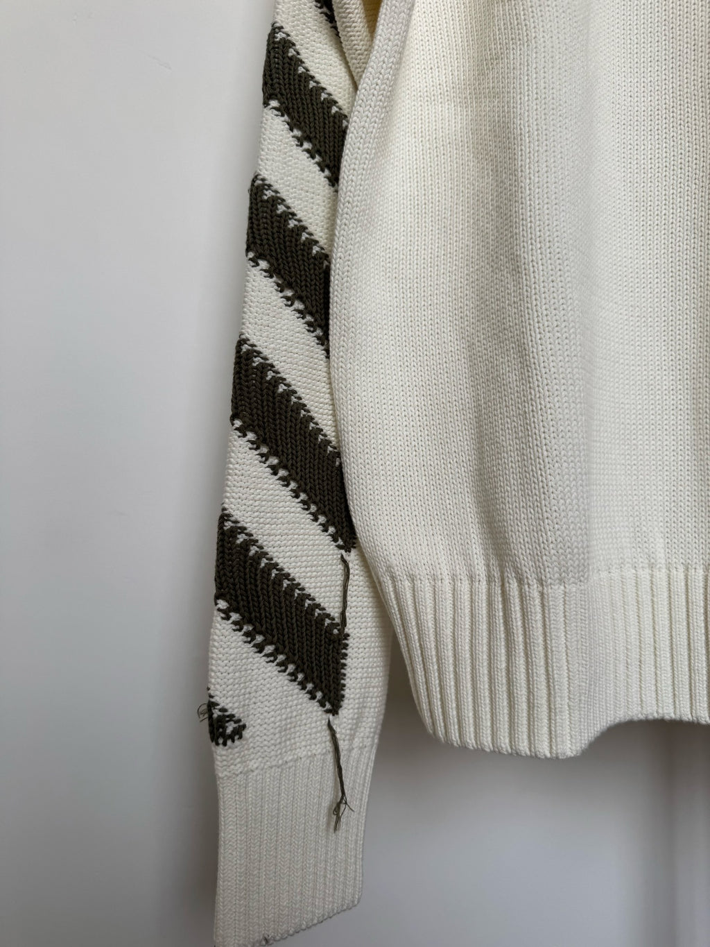 Off-white sweater with black diagonal stripe-knit panel on one sleeve
