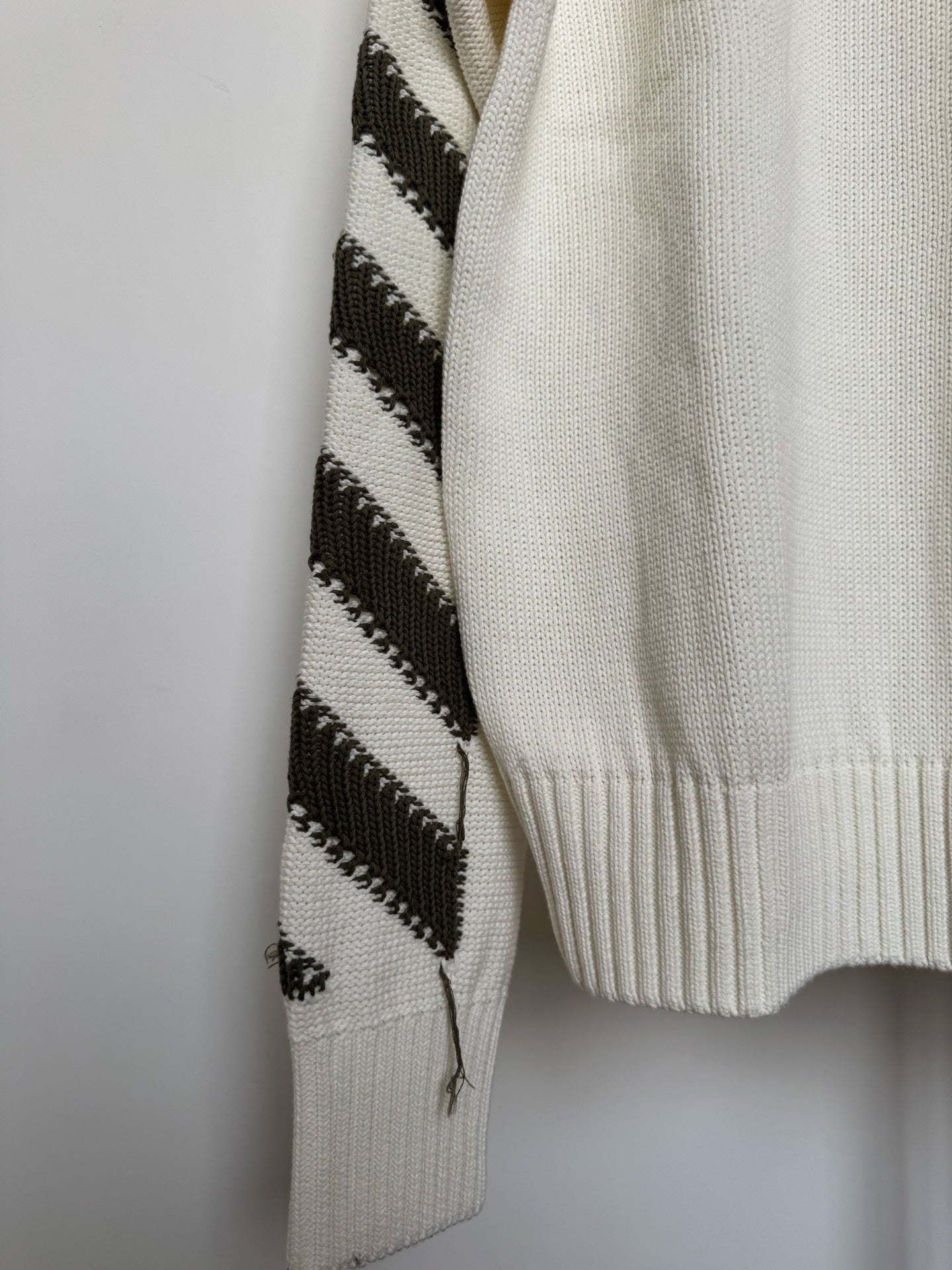 Off-white sweater with black diagonal stripe-knit panel on one sleeve