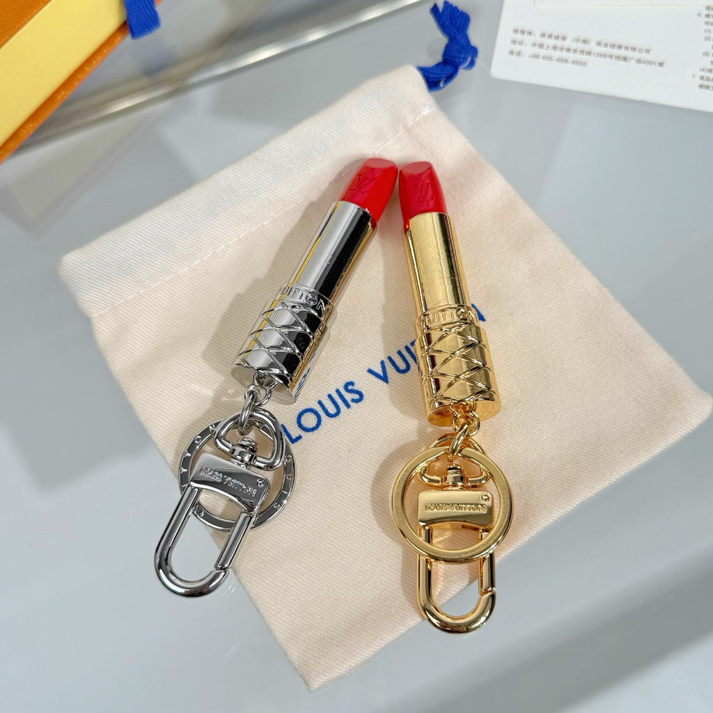 Lipstick-shaped keychains on white pouch: one silver, one gold, both red tips