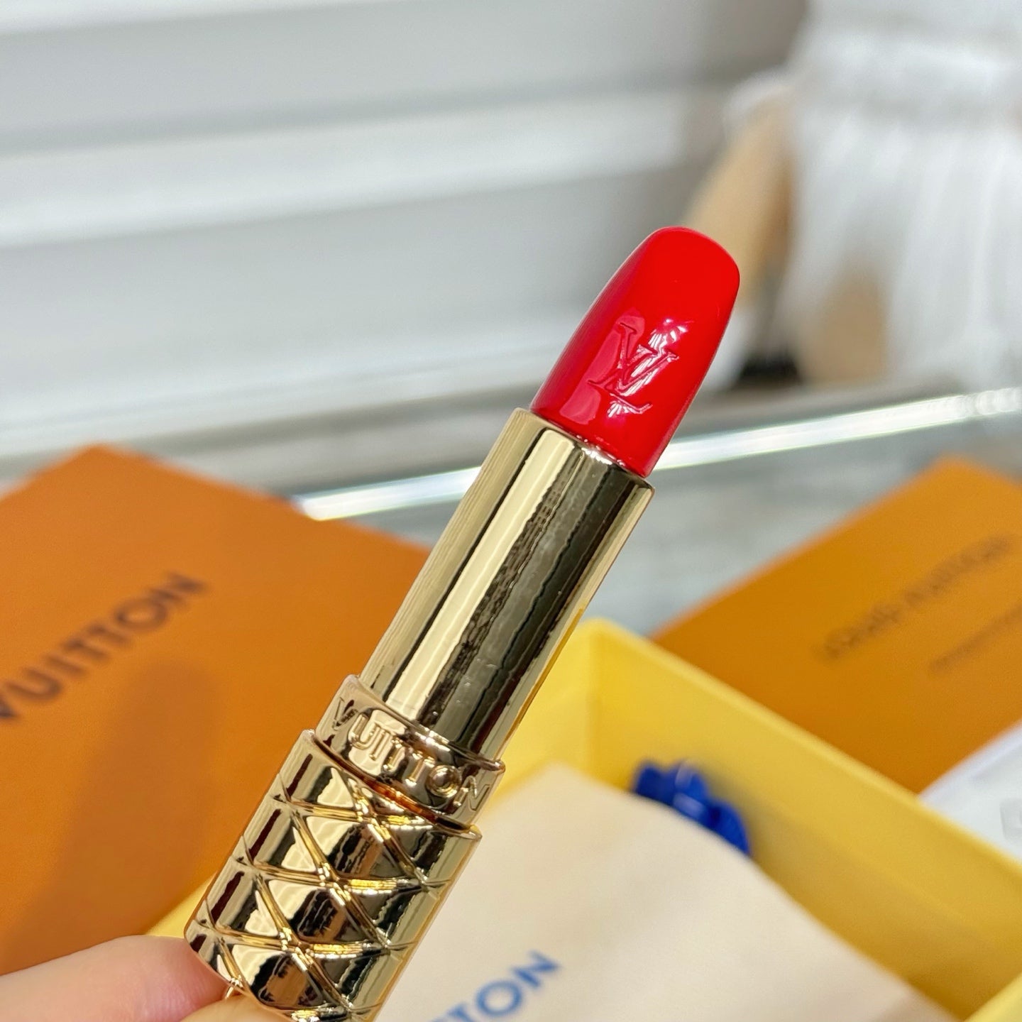 Small bag charm with gold lipstick pendant and glossy red cap, close-up metal clasp