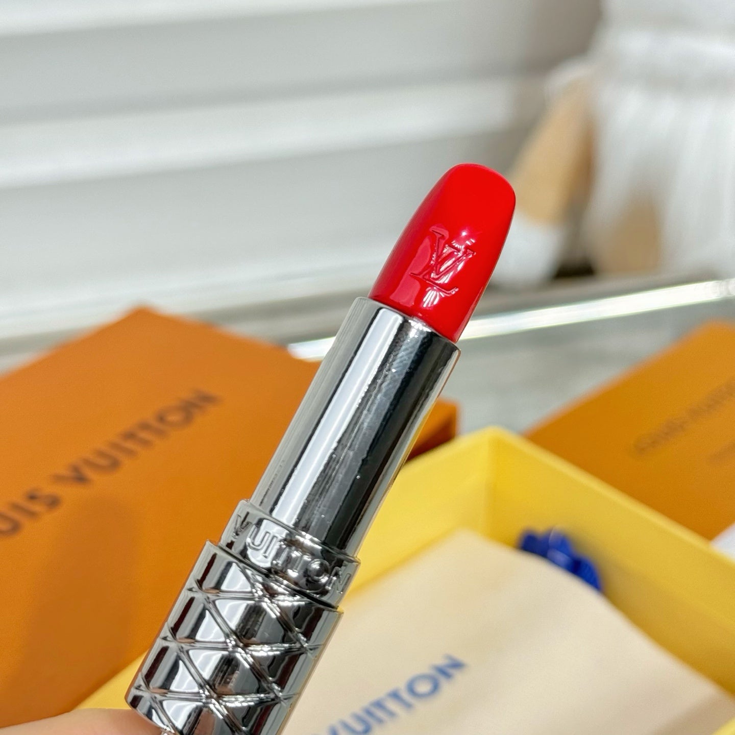 Small bag charm with silver lipstick pendant and glossy red cap, close-up metal clasp