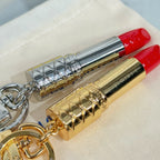 Two lipstick-shaped keychains on pouch: silver and gold bodies with red caps