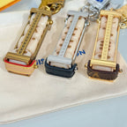 Close-up of three Louis Vuitton mini bag charm keychains with padlock clasps