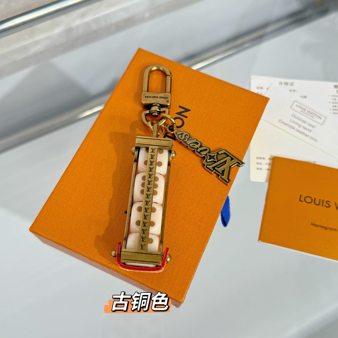 Louis Vuitton mini bag charm keychain on orange box with antique bronze hardware