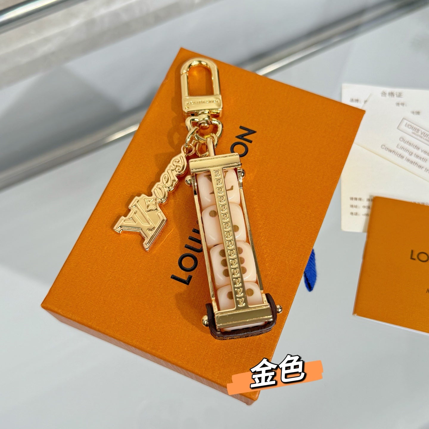 Louis Vuitton keychain with gold lock charm and patterned monogram strap on an orange box