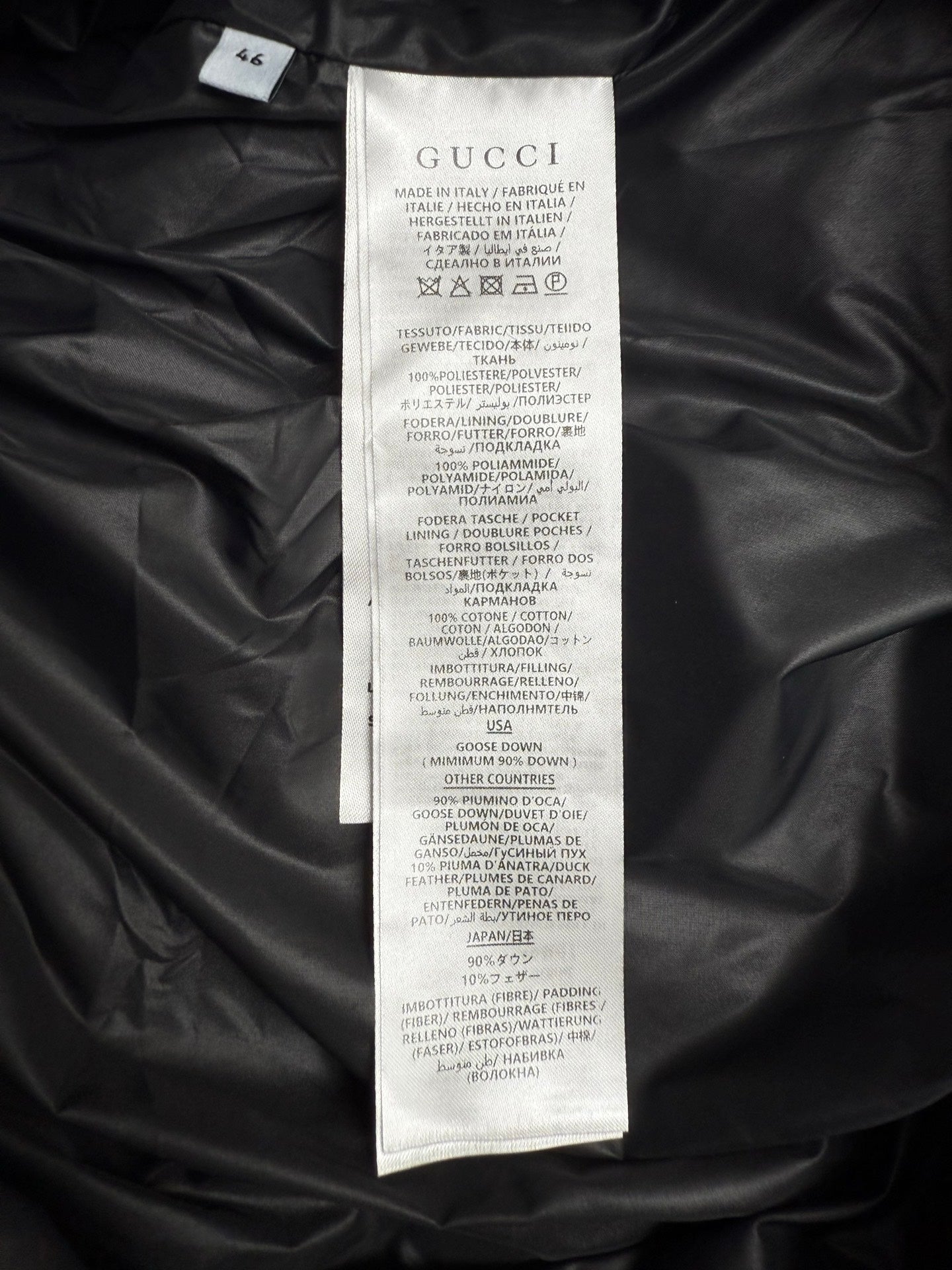 GUCCI clothing care label on black padded jacket, with size and fabric info