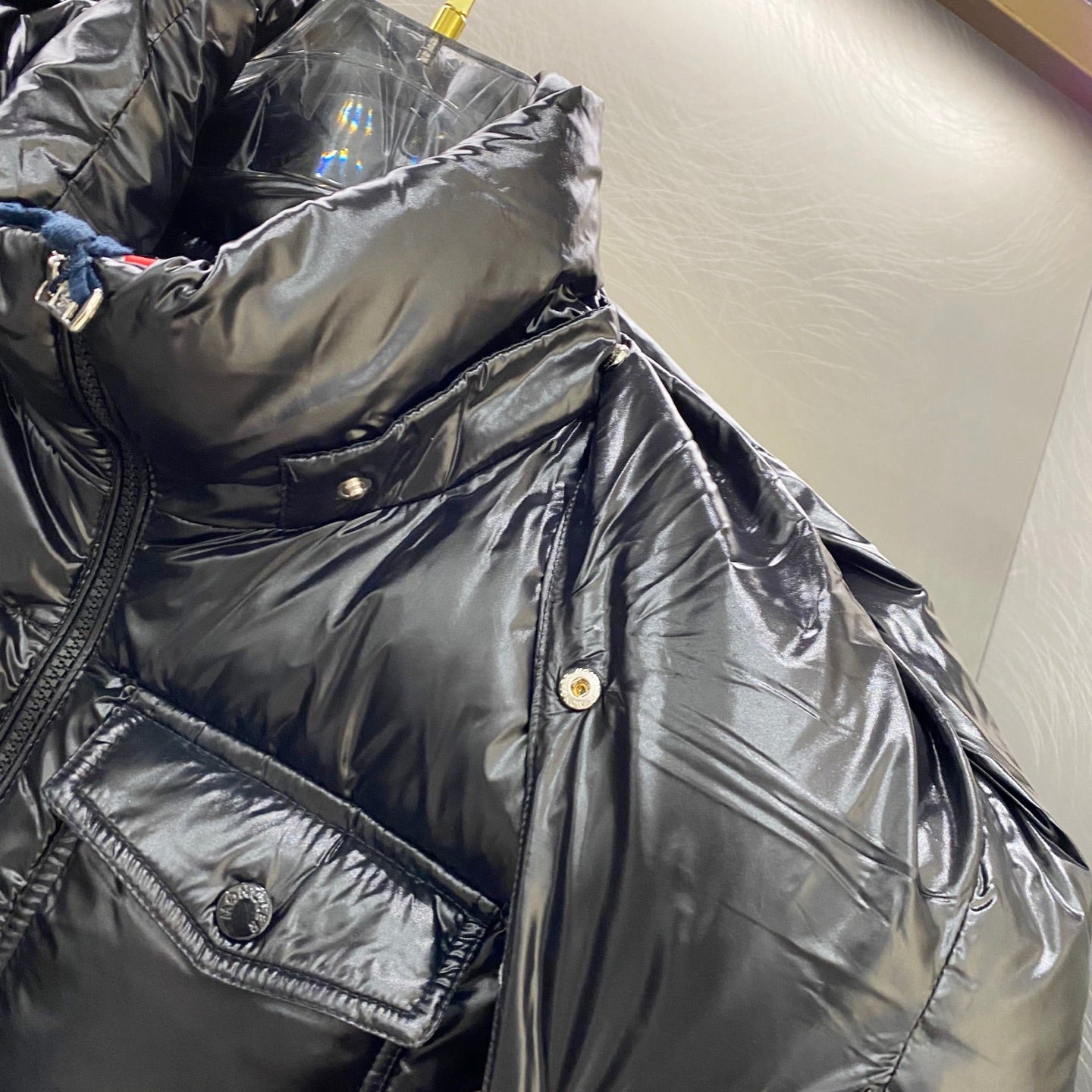 Moncler long padded jacket detail: dark chest area with pocket flap and snaps