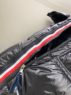 Moncler long padded jacket close-up: dark front zipper with red and white stripe