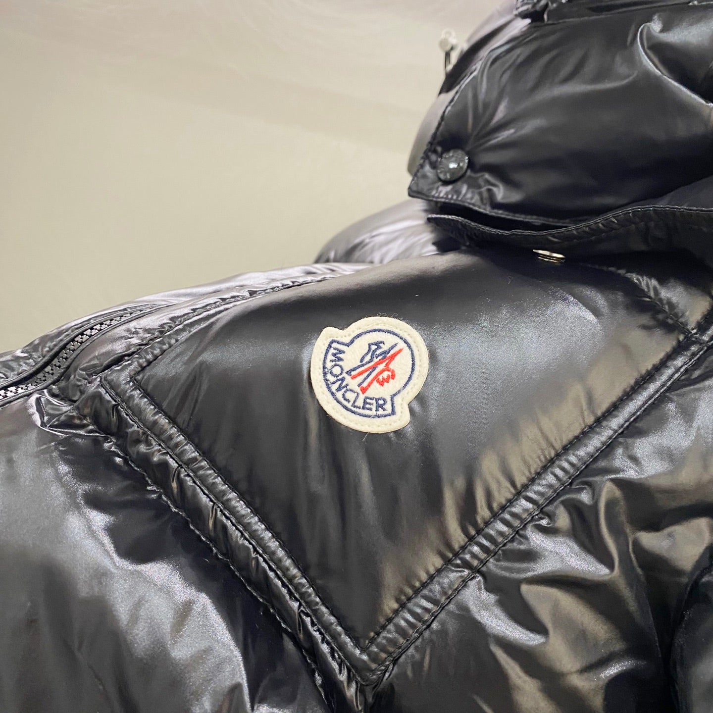 Moncler jacket logo patch on dark quilted shoulder, with stitched trim