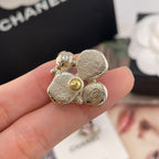 Chanel-style charm earrings close-up, gold-tone glitter petals with faux pearl and charm