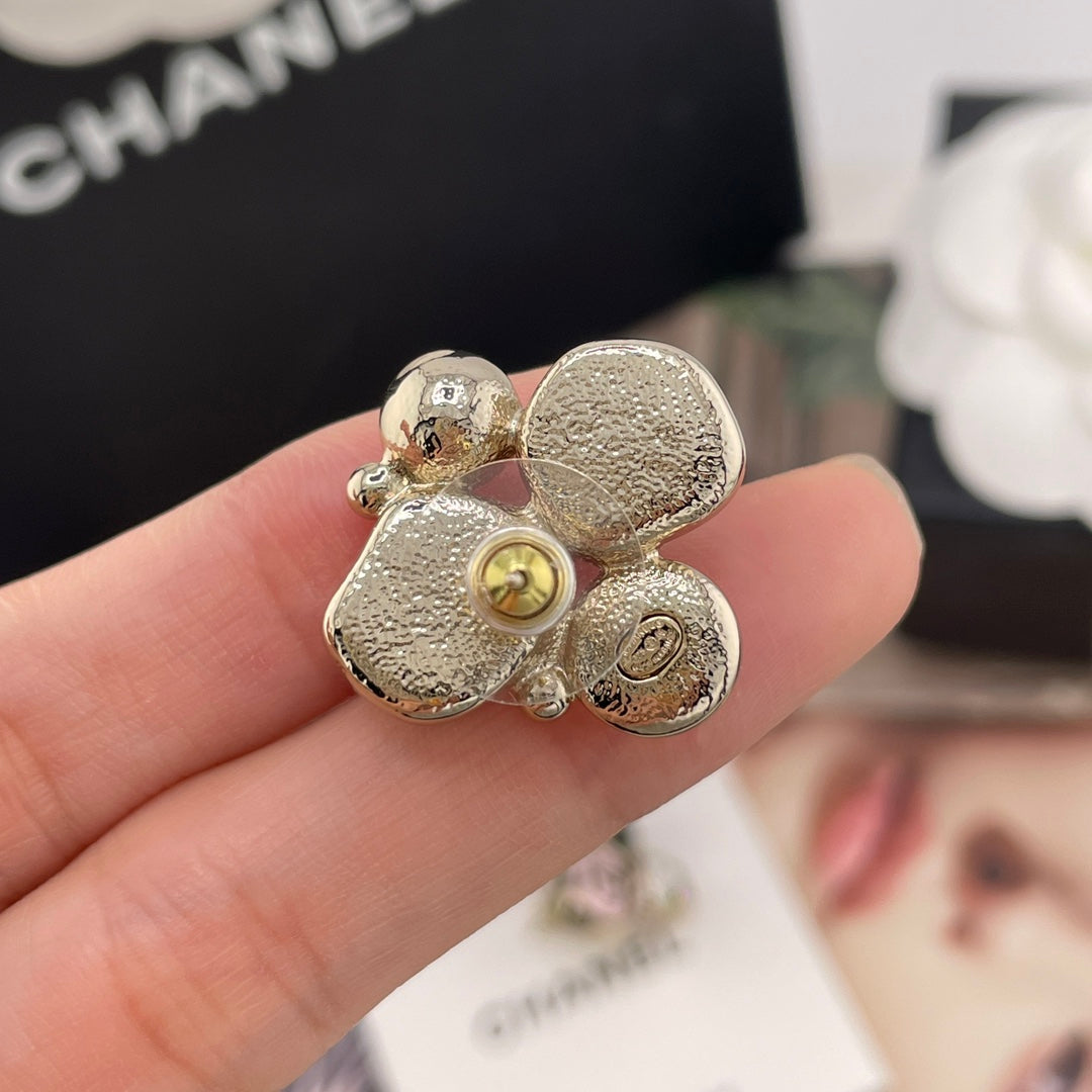 Chanel-style charm earrings close-up, gold-tone glitter petals with faux pearl and charm