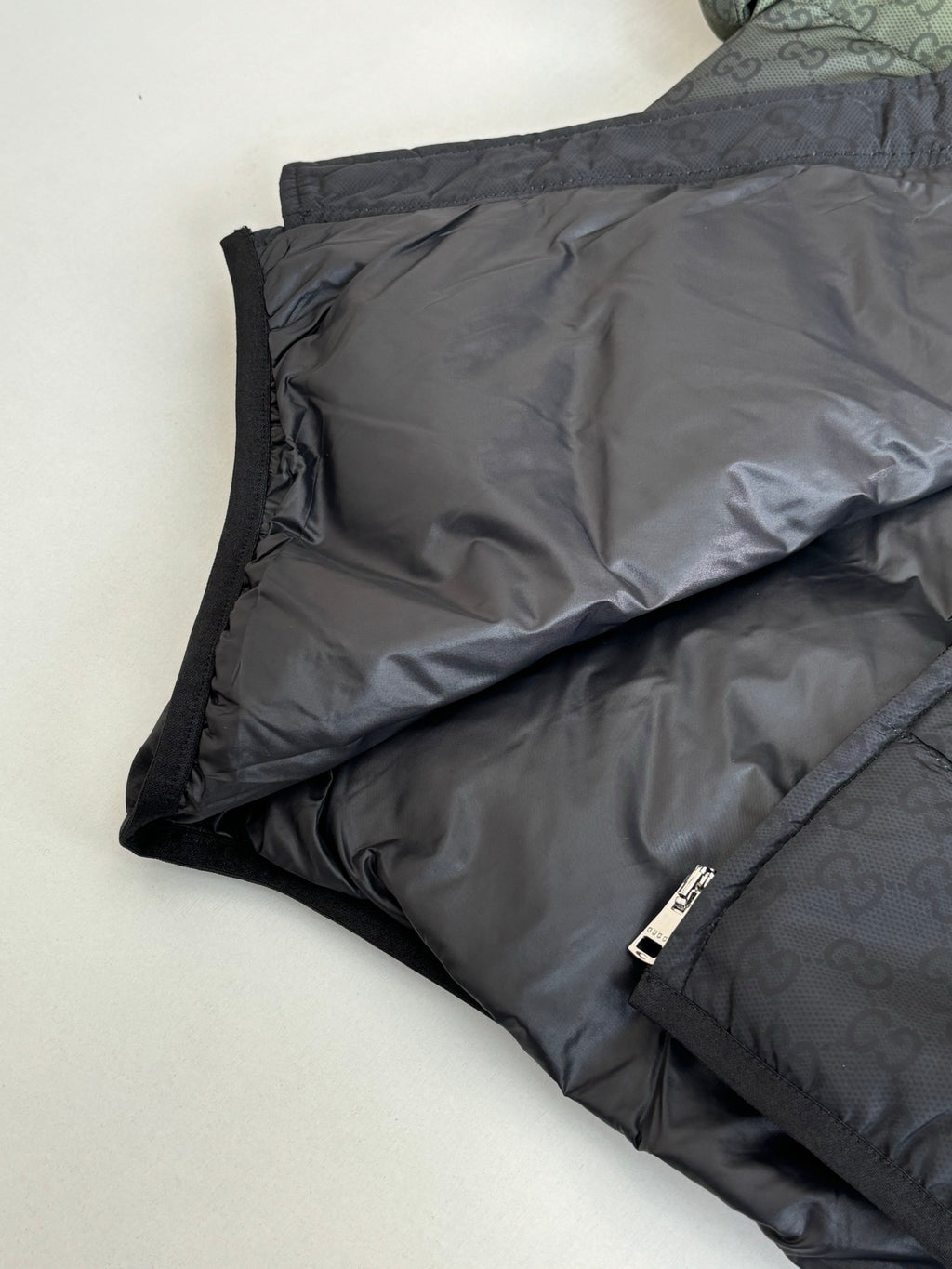 Folded dark puffer jacket with black zipper and quilted interior lining