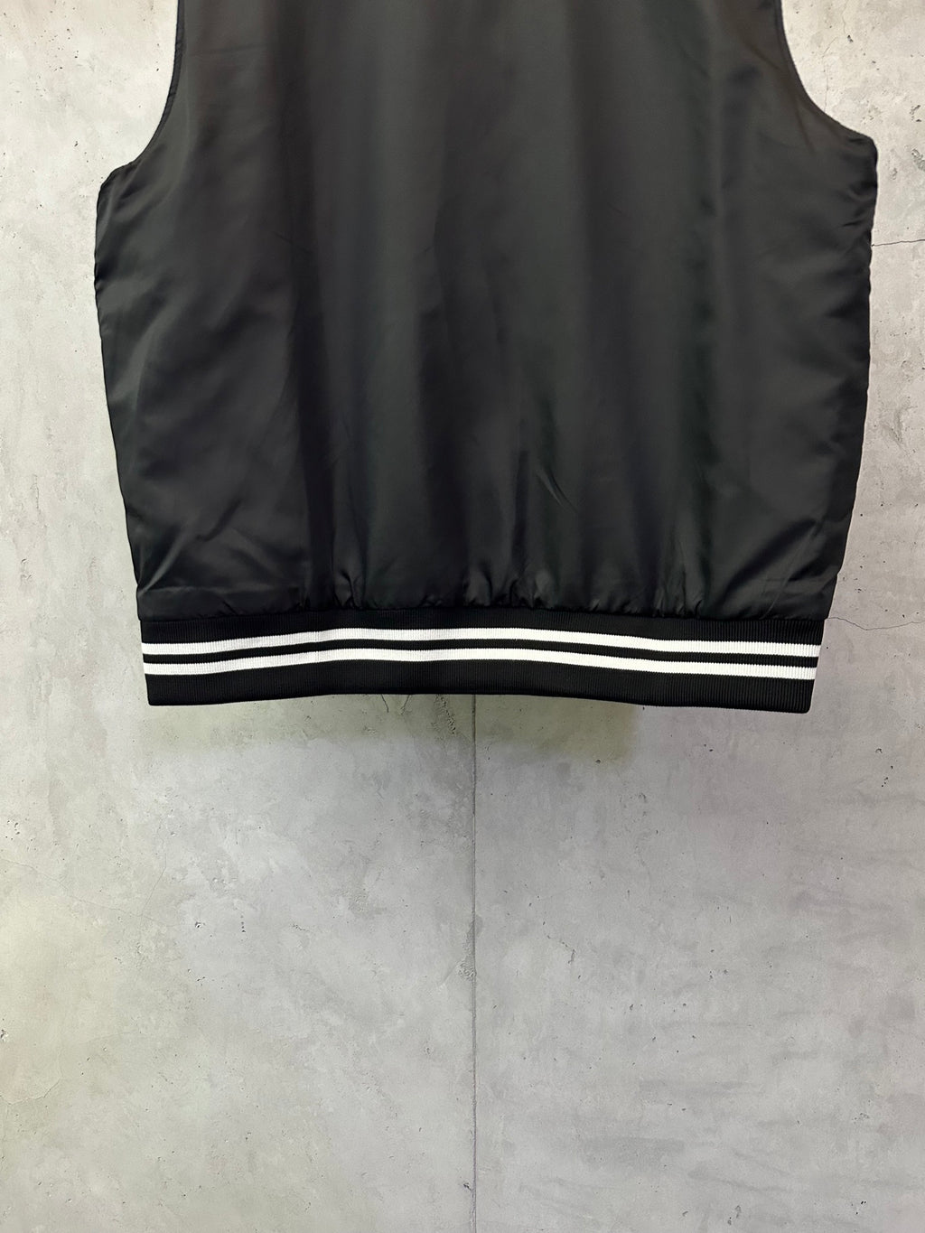 Sleeveless dark bomber vest with striped ribbed hem and smooth fabric