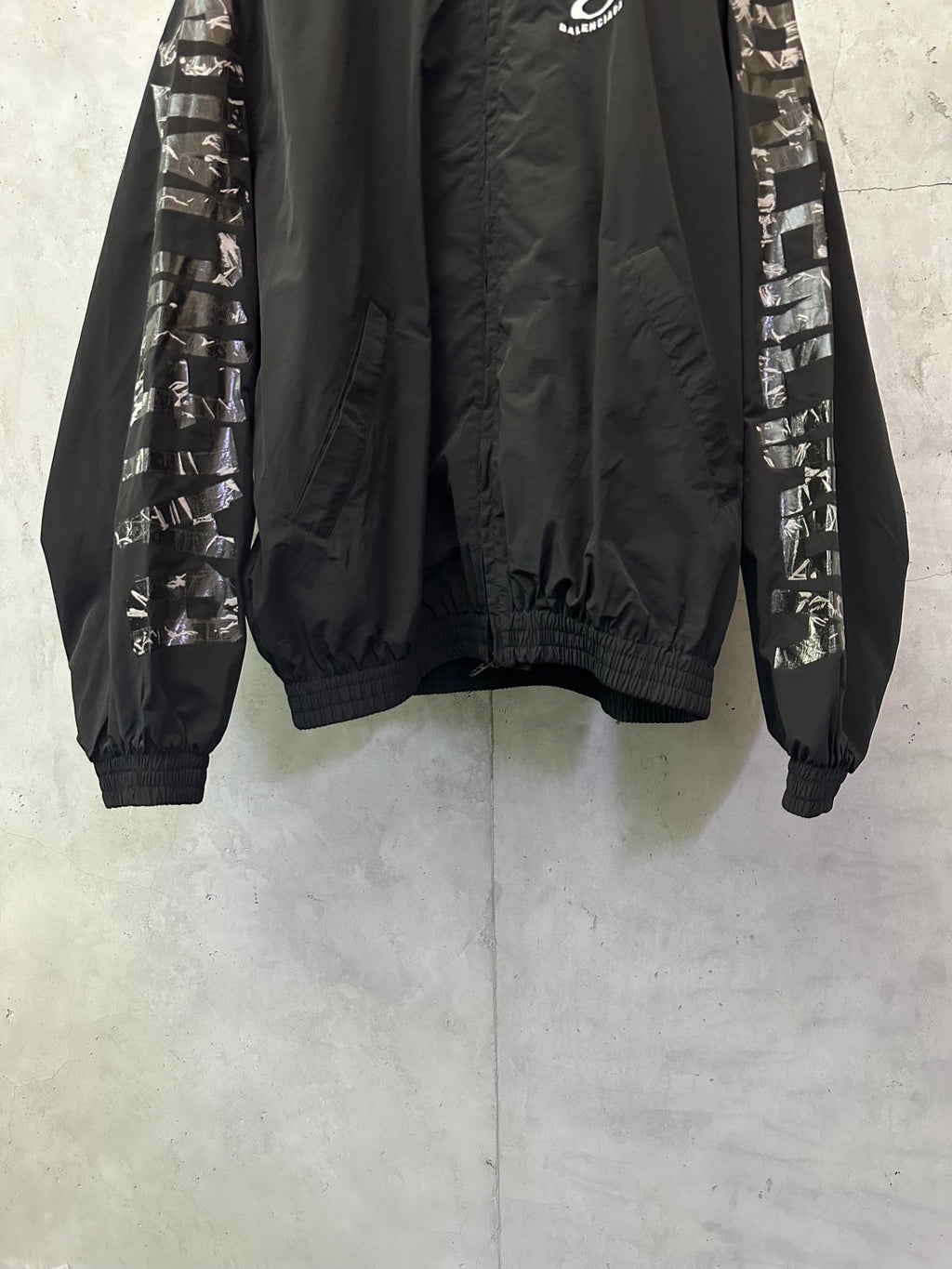 Black bomber jacket with graphic sleeve bands, high collar, ribbed cuffs and hem