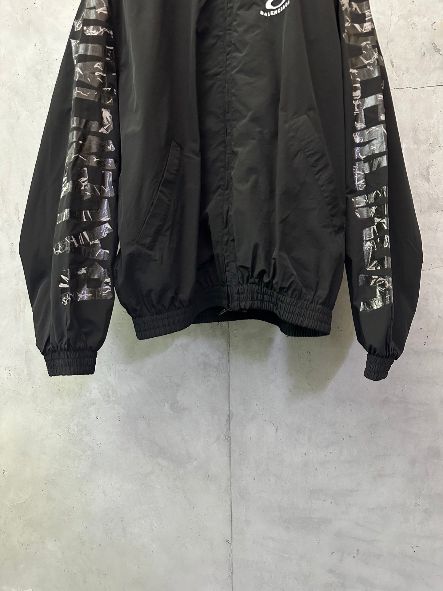 Black bomber jacket with graphic sleeve bands, high collar, ribbed cuffs and hem