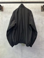 Black long bomber jacket, back view, relaxed shoulders, gathered hem cuffs