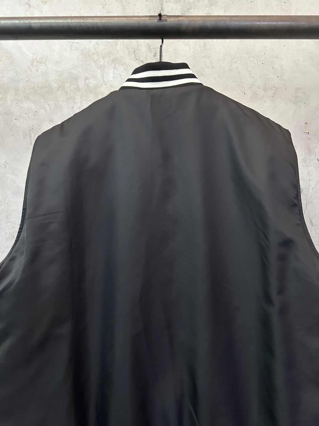 Sleeveless dark bomber vest back view with striped collar detail