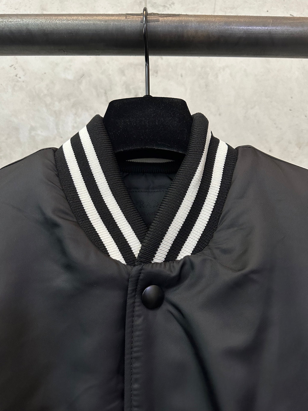 Sleeveless dark bomber vest with striped V-collar and black button