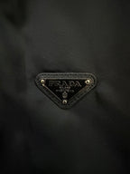 Prada triangular logo patch on dark fabric
