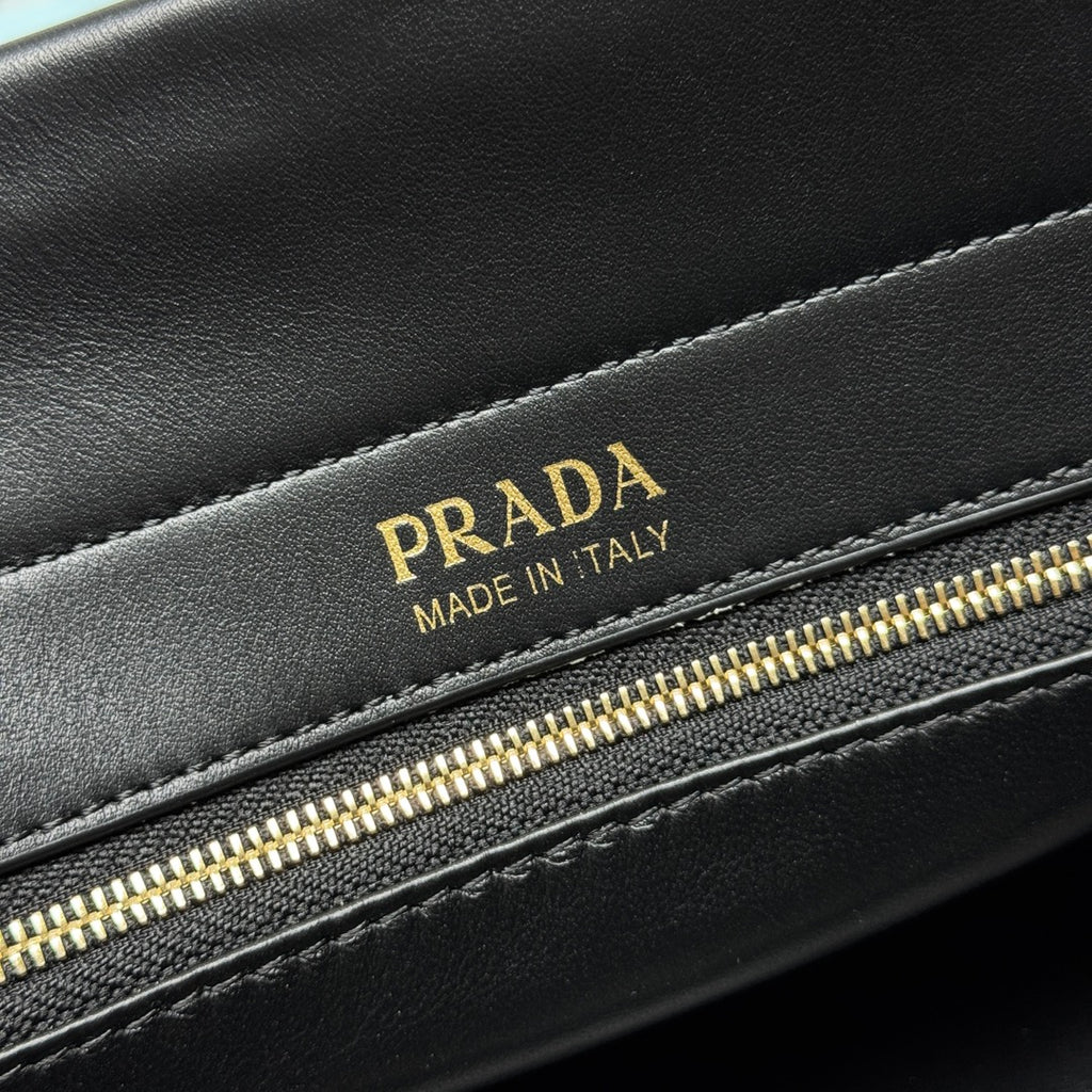 Prada Made in Italy leather label on black bag with gold zipper detail.