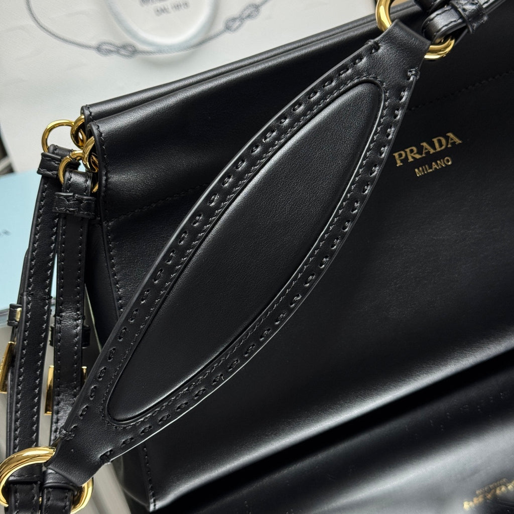 Prada black leather bag side with perforated trim and gold-tone strap hardware.