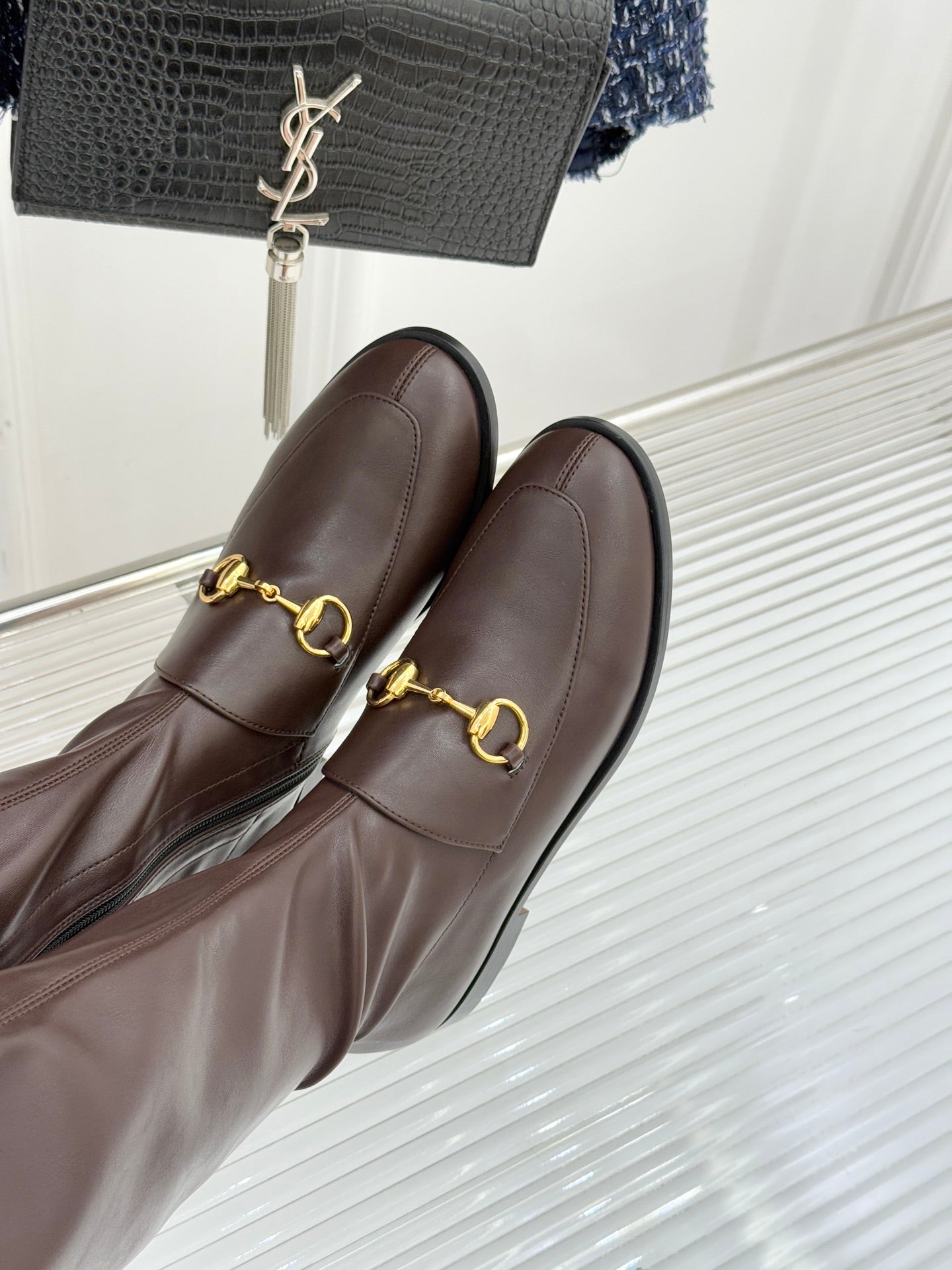 Close-up of Gucci ladies knee-high leather boots with gold-tone bit detail