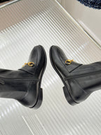 Black leather boots with gold horsebit straps, front profile view