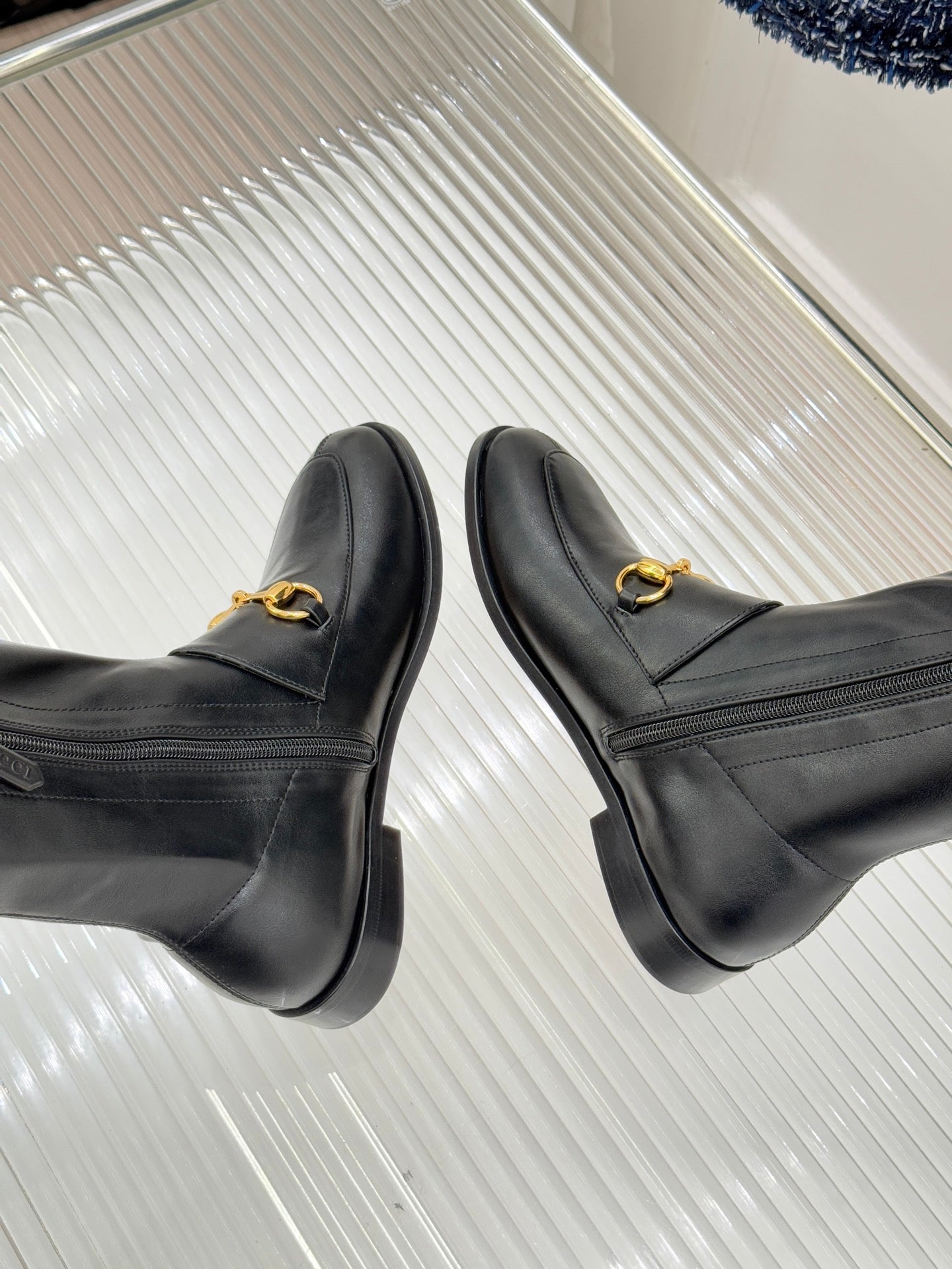 Black leather boots with gold horsebit straps, front profile view